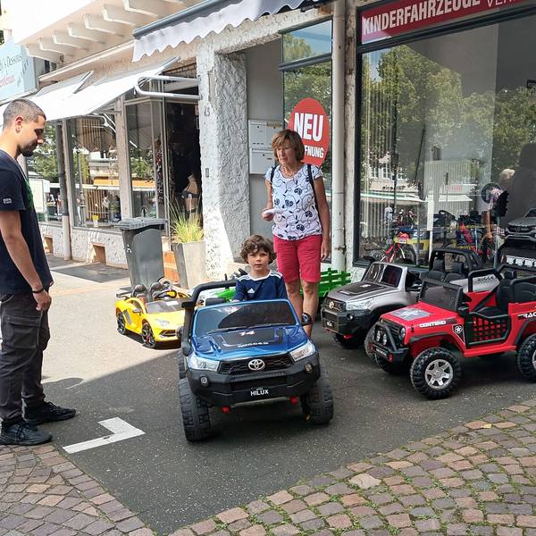 Zwei Erwachsene und ein Kind in einem Miniauto auf dem Siegburger Markt