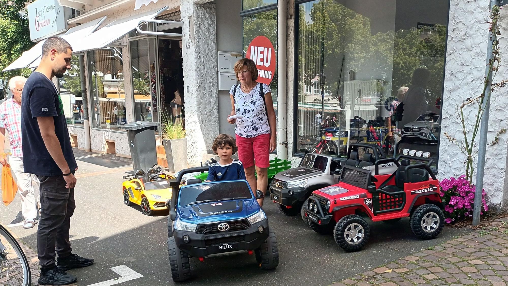 Zwei Erwachsene und ein Kind in einem Miniauto auf dem Siegburger Markt
