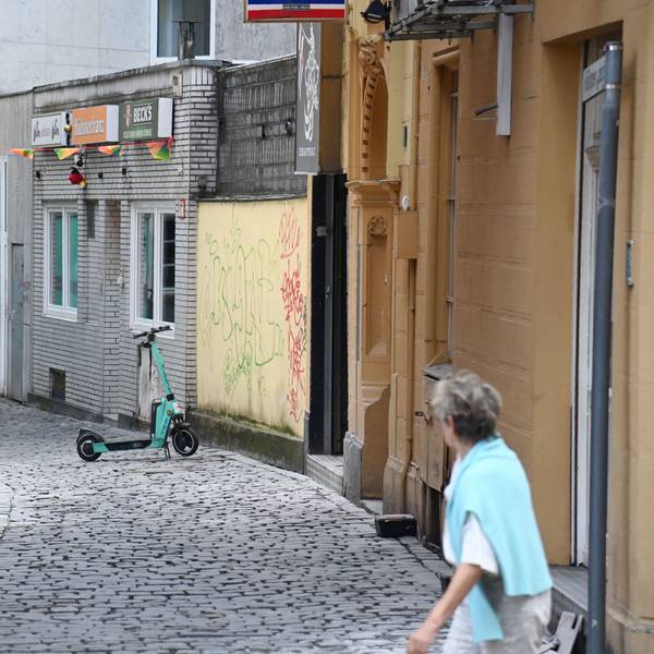 Eine Frau schaut in die Hühnergasse mit beschmierten und zugenagelten Häuserfassaden.