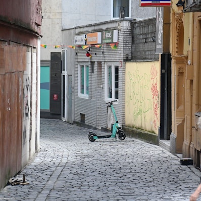 Eine Frau schaut in die Hühnergasse mit beschmierten und zugenagelten Häuserfassaden.