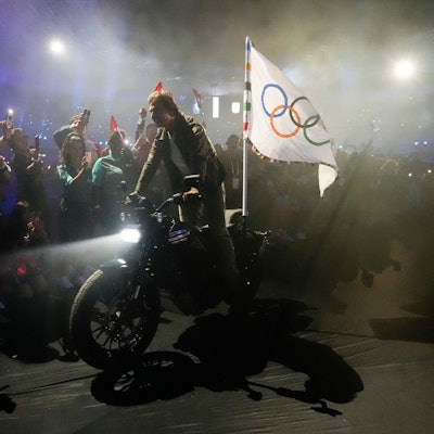 11.08.2024, Frankreich, Saint-Denis: Tom Cruise fährt auf einem Motorrad mit der olympischen Flagge während der Abschlussfeier der Olympischen Sommerspiele 2024 im Stade de France.