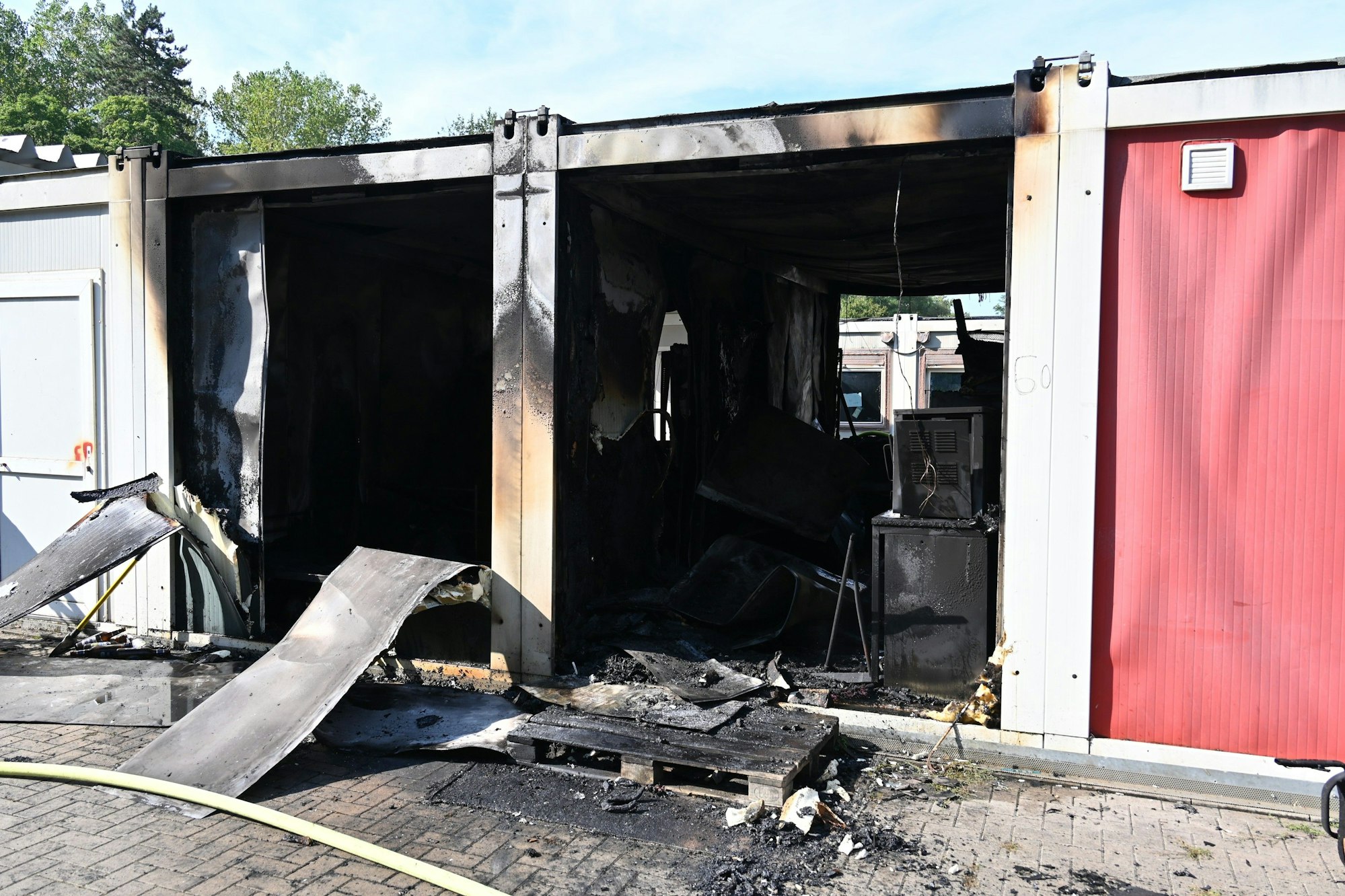 Auf dem Bild sind zwei ausgebrannte Wohncontainer zu sehen.