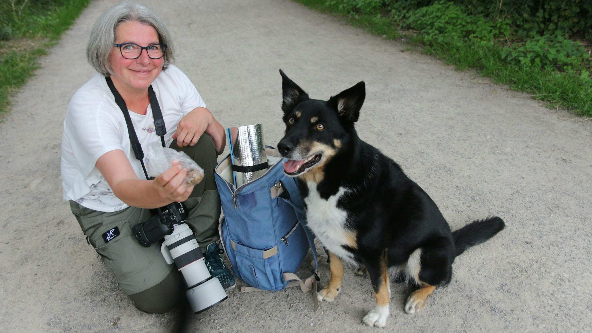 Auf dem Bild ist eine Fotografin mit Ausrüstung und einem Hund zu sehen.