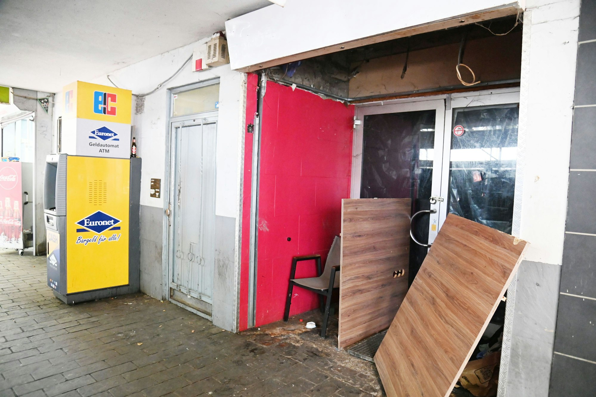 Neben einem Geldautomaten ist ein Obdachlosenquartier vor einem leerstehenden Erdgeschoss