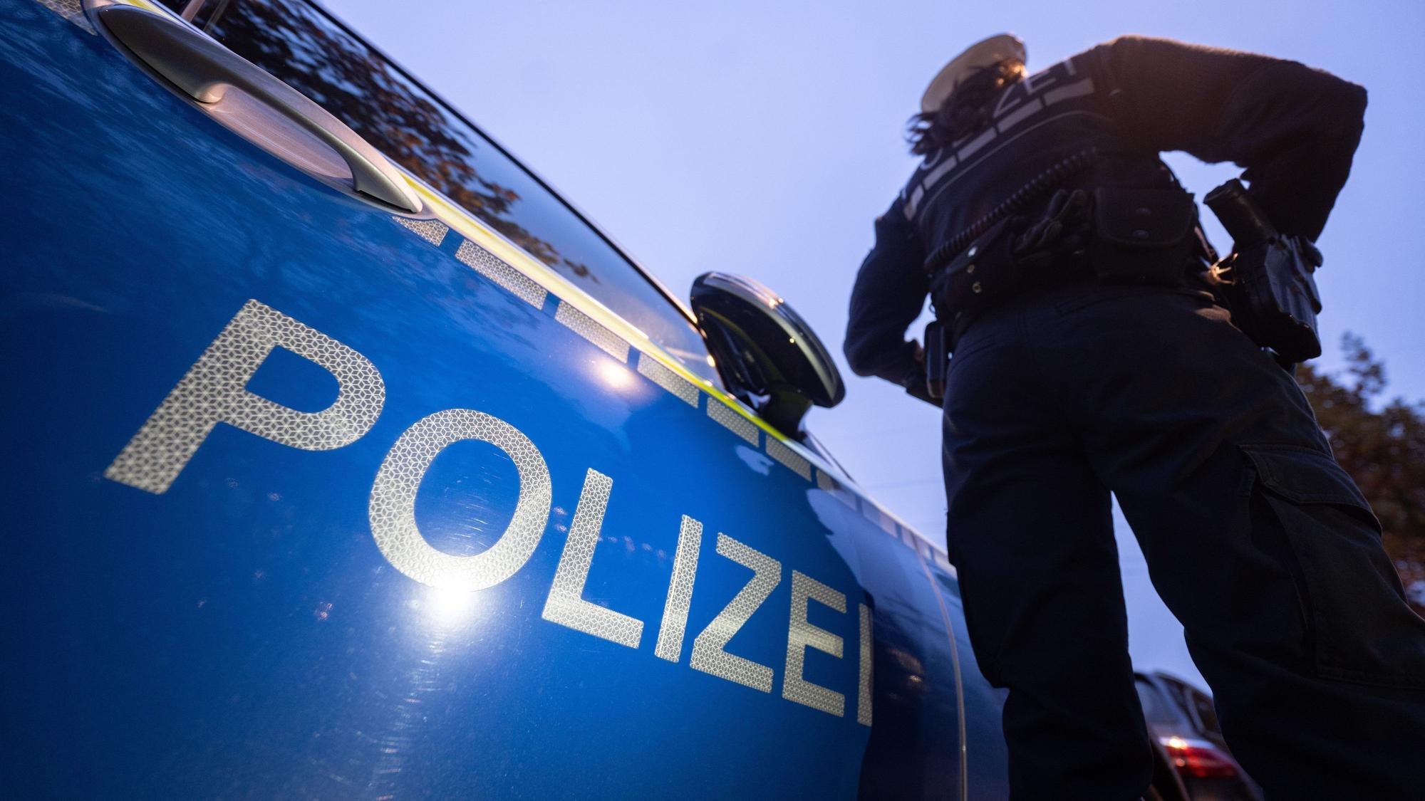 Das Bild zeigt einen Polizeibeamten an einerm Streifenwagen.