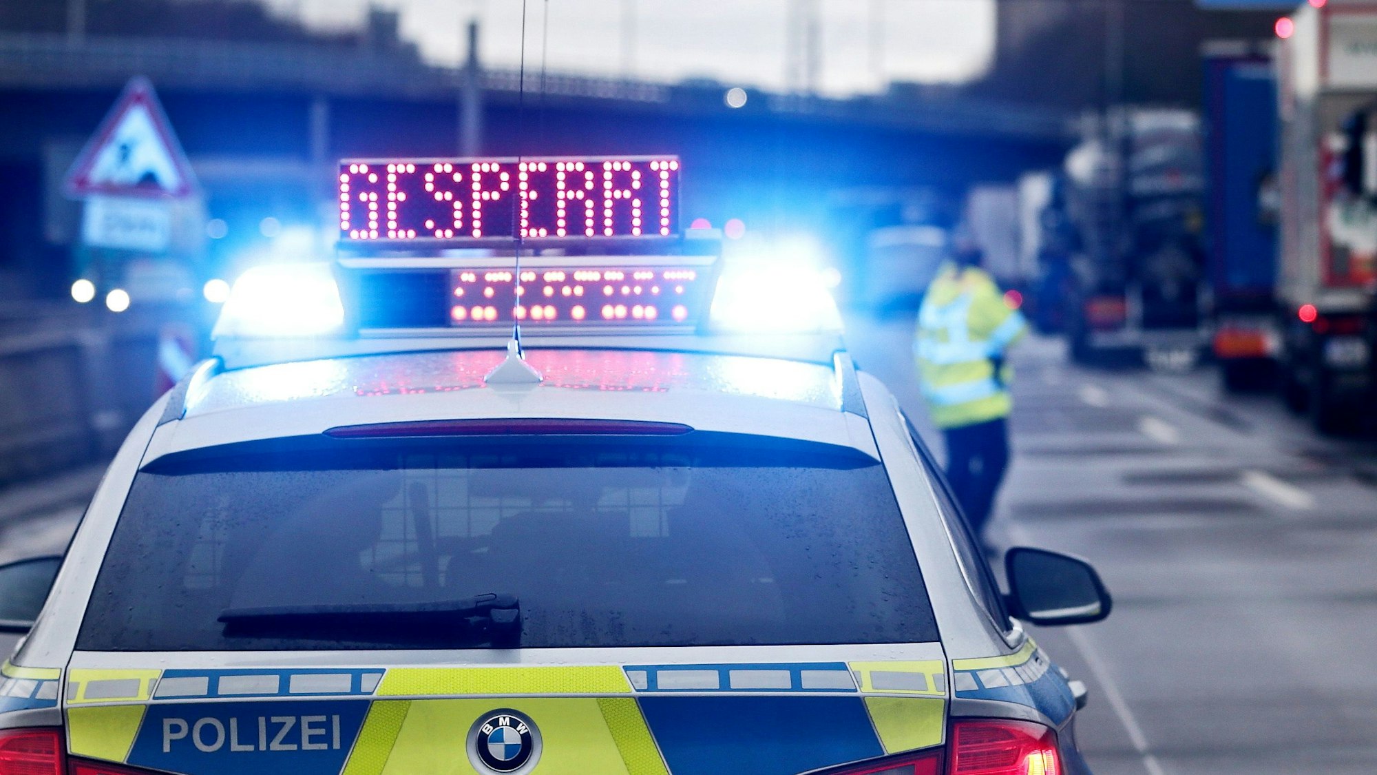 Auf einem Polizeifahrzeug leuchtet die Aufschrift 'Gesperrt'.