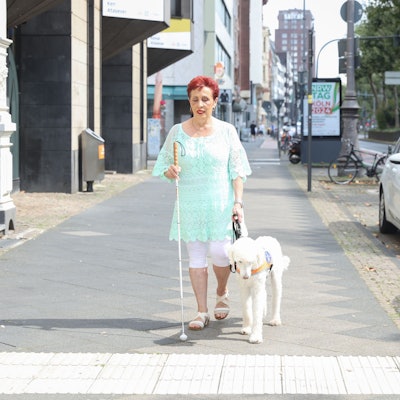 Die blinde Marisa Sommer geht mit ihrem Blindenführhund Reiner durch Köln.