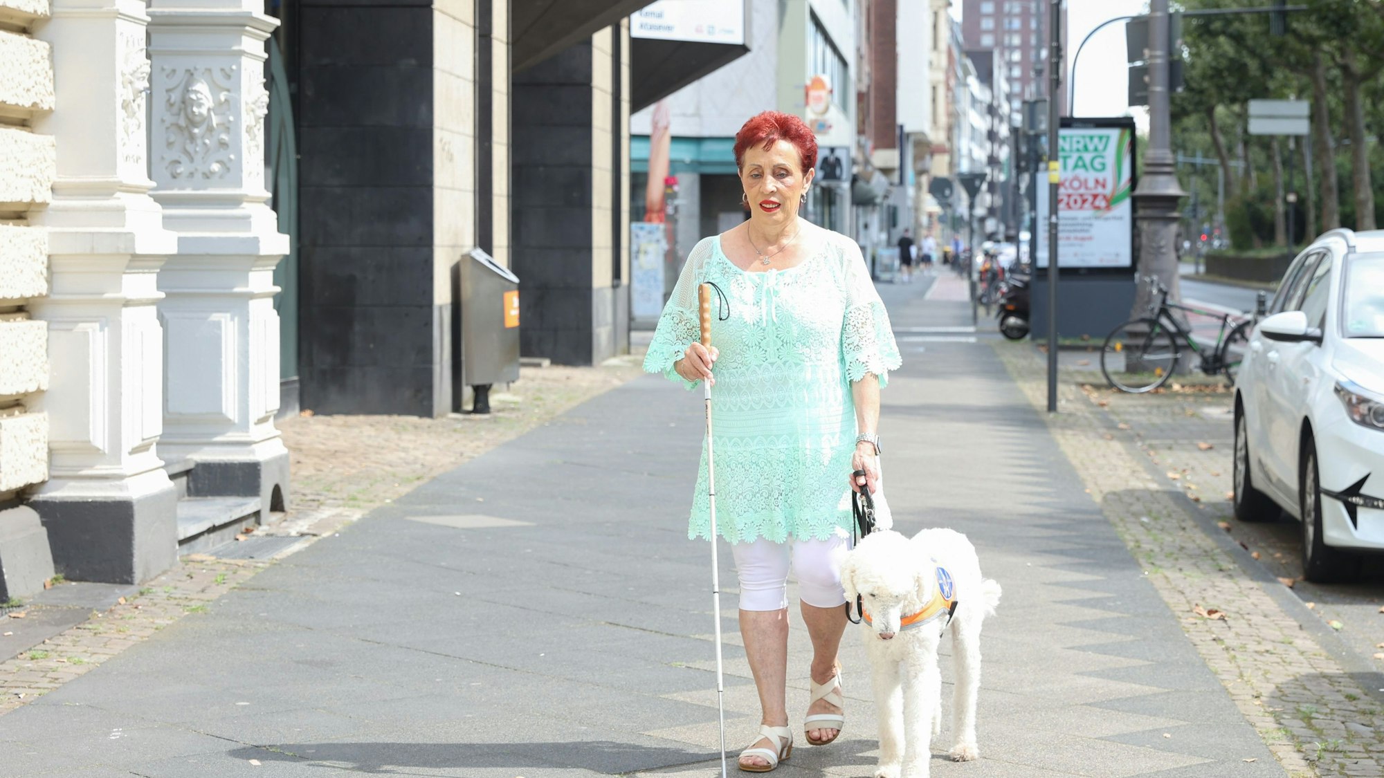 Die blinde Marisa Sommer geht mit ihrem Blindenführhund Reiner durch Köln.
