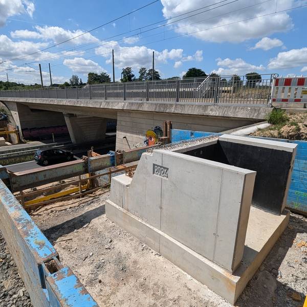 Ein Brückenfundament mit der eingegossenen Jahreszahl 2024 neben einer Brücke über eine vierspurige Straße.