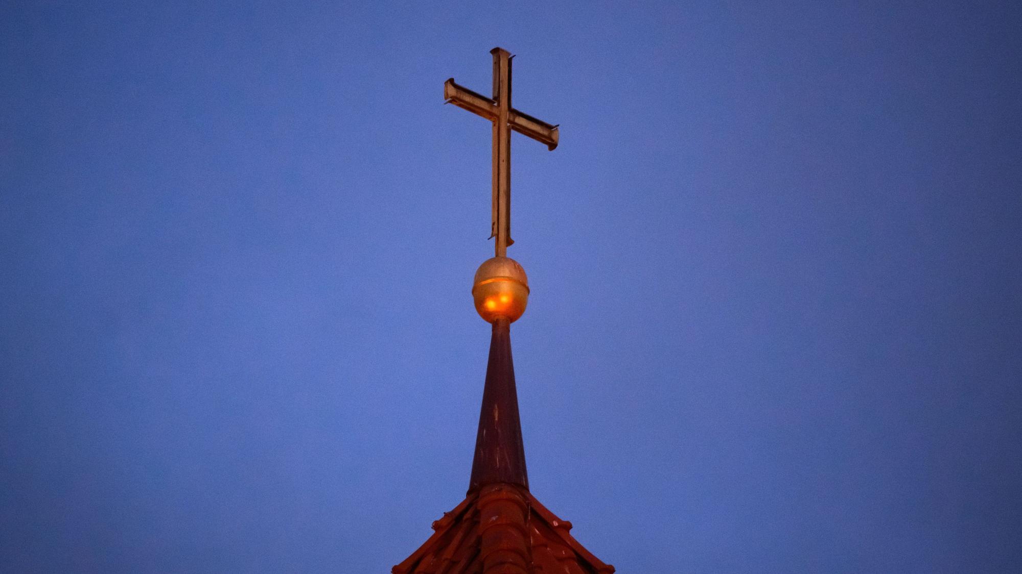 Ein Kreuz steht auf der Kirchturmspitze einer evangelischen Kirche in der Region Hannover. (Symbolbild)