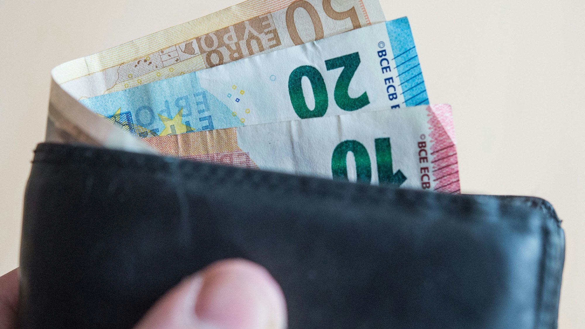 Eine Person hält ein Portemonnaie mit Geld in der Hand. (Symbolbild)