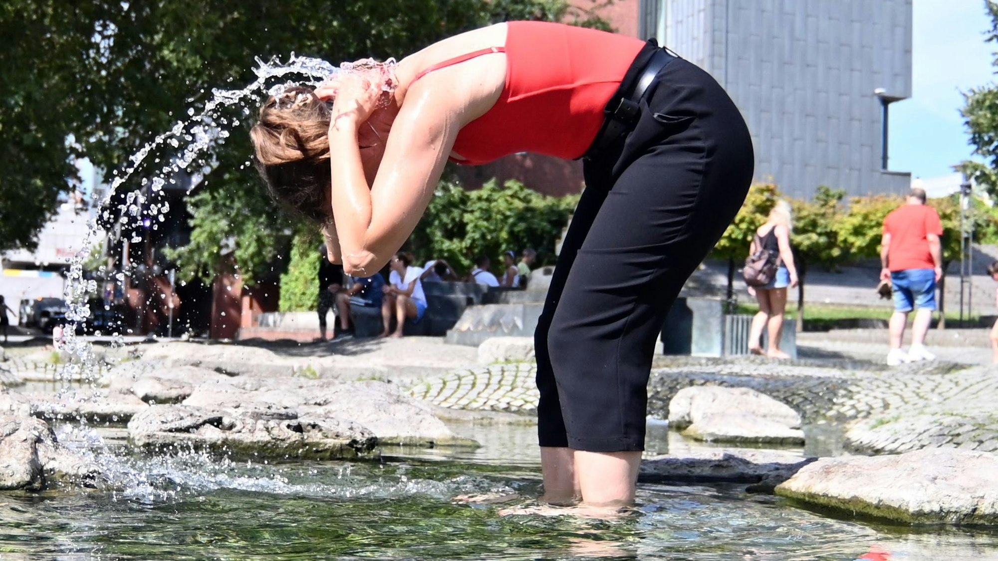 Eine Kölnerin erfrischt sich am Wasserspielplatz in der Altstadt.