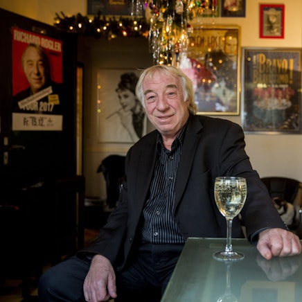 Richard Rogler sitzt vor einem Glas Wein in einer Kneipe.