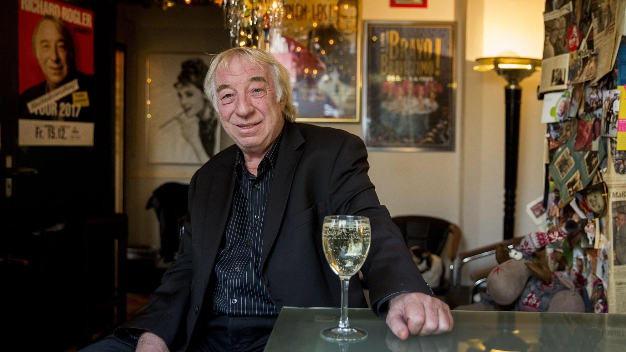 Richard Rogler sitzt vor einem Glas Wein in einer Kneipe.