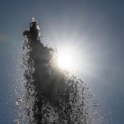 Die Sonne scheint hinter der Wasserfontäne vor der Alten Oper in Frankfurt.
