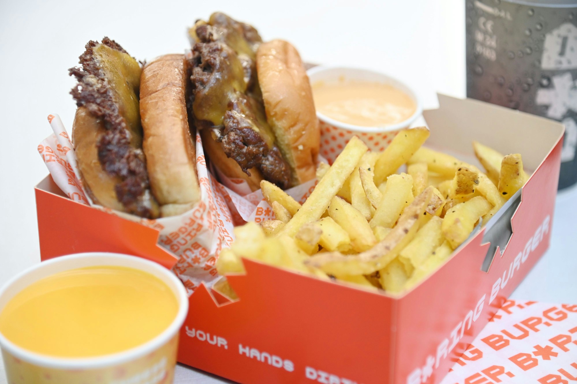 Der „Smashed Burger“ mit Fritten und Getränk im Take-Away-Karton