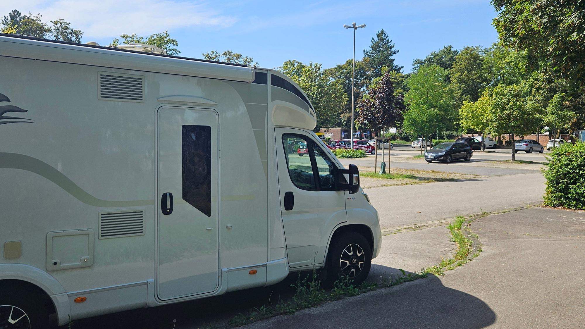 Ein Wohnmobil steht auf einem Parkplatz in Kaster.
