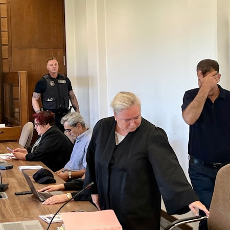 Ein Angeklagter hält sich im Kölner Landgericht die Hand vor das Gesicht.