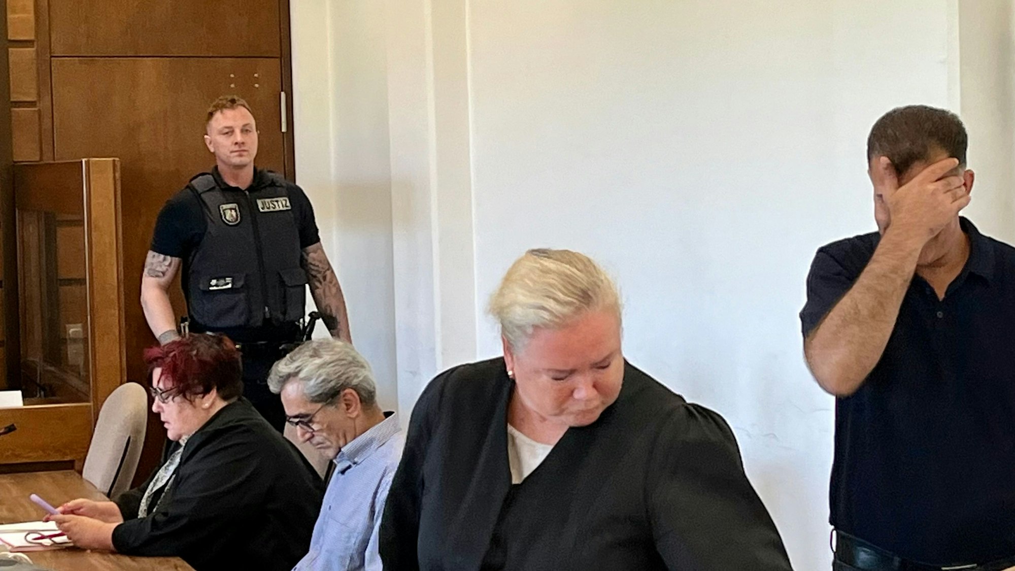 Ein Angeklagter im Prozess um die tödliche Messerstecherei am 18. Februar 2024 in Schlebusch hält sich im Gerichtssaal die Hand vors Gesicht.