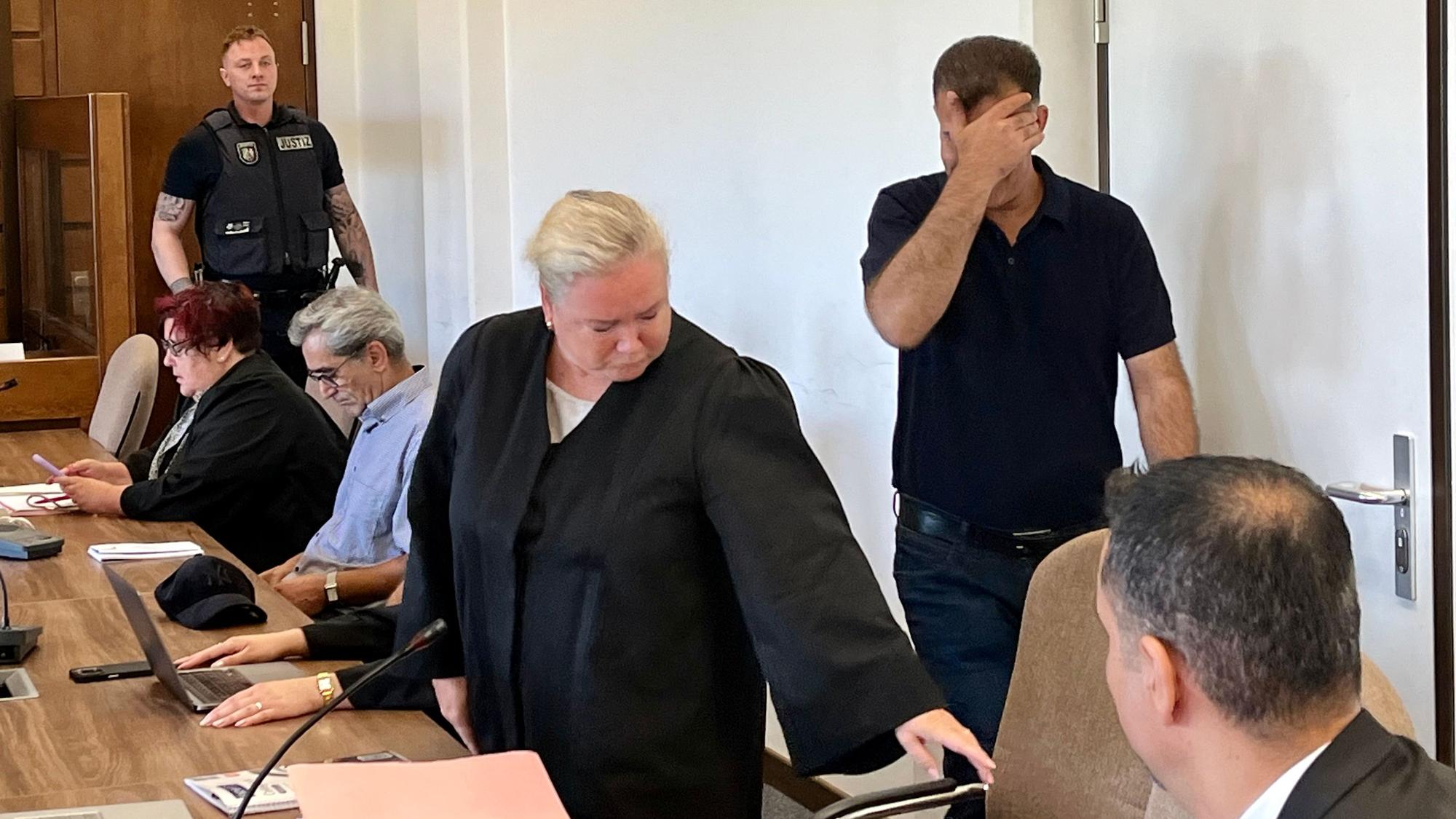 Ein Angeklagter hält sich im Kölner Landgericht die Hand vor das Gesicht.
