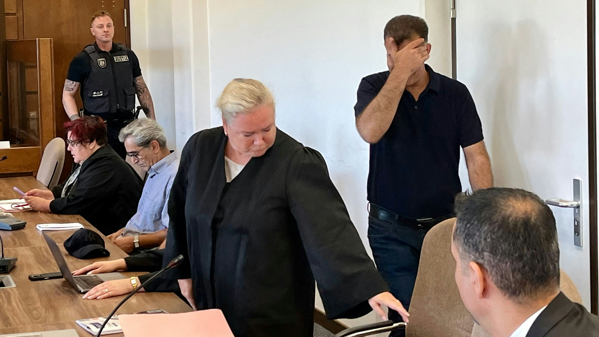 Ein Angeklagter hält sich im Kölner Landgericht die Hand vor das Gesicht.