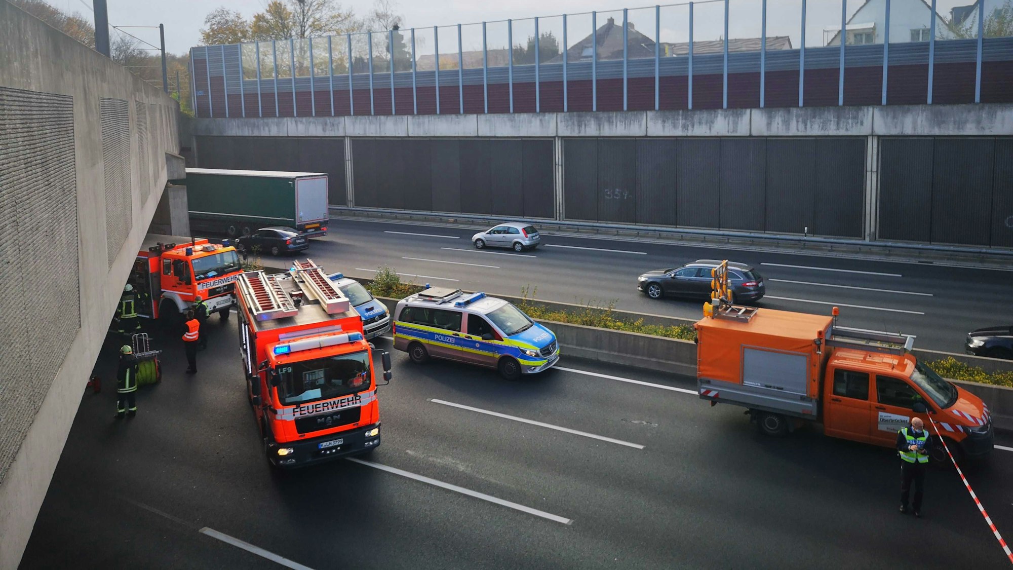 Einsatzfahrzeuge von Feuerwehr und Polizei stehen auf der Autobahn A3 in Höhe der Wichheimer Straße, wo die Lärmschutzwand auf das Fahrzeug fiel. (Archivbild)