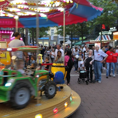 Ein Kinderkarussell auf einem Stadtfest mit einem grünen Traktor
