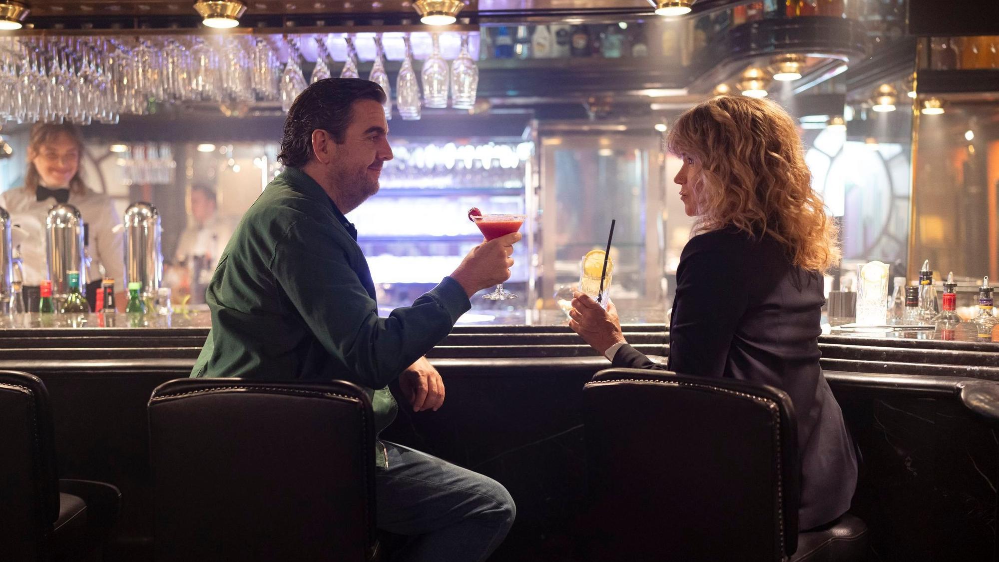 Bastian Pastewka und Anke Engelke prosten sich an einer Hotelbar in ihren als Ralf und Maria in der Serie „Perfekt Verpasst“ zu.