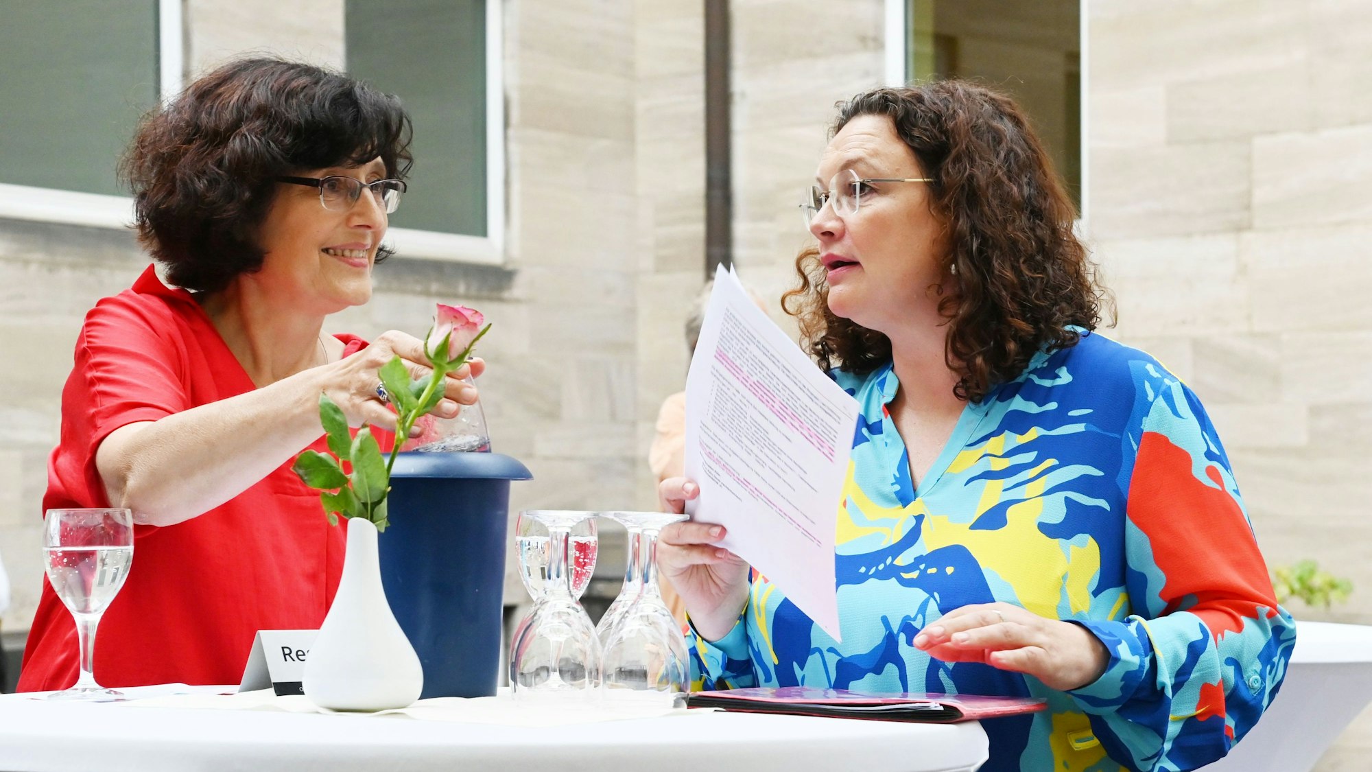 Andrea Nahles und Claudia Walther stehen an einem Stehtisch und diskutieren.
