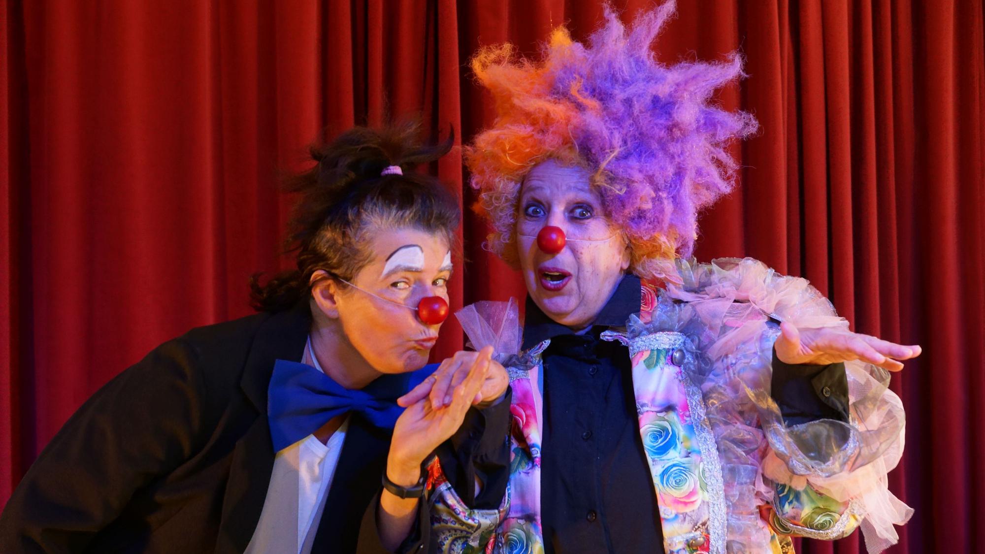 Zwei Clowninnen stehen auf einer Bühne.