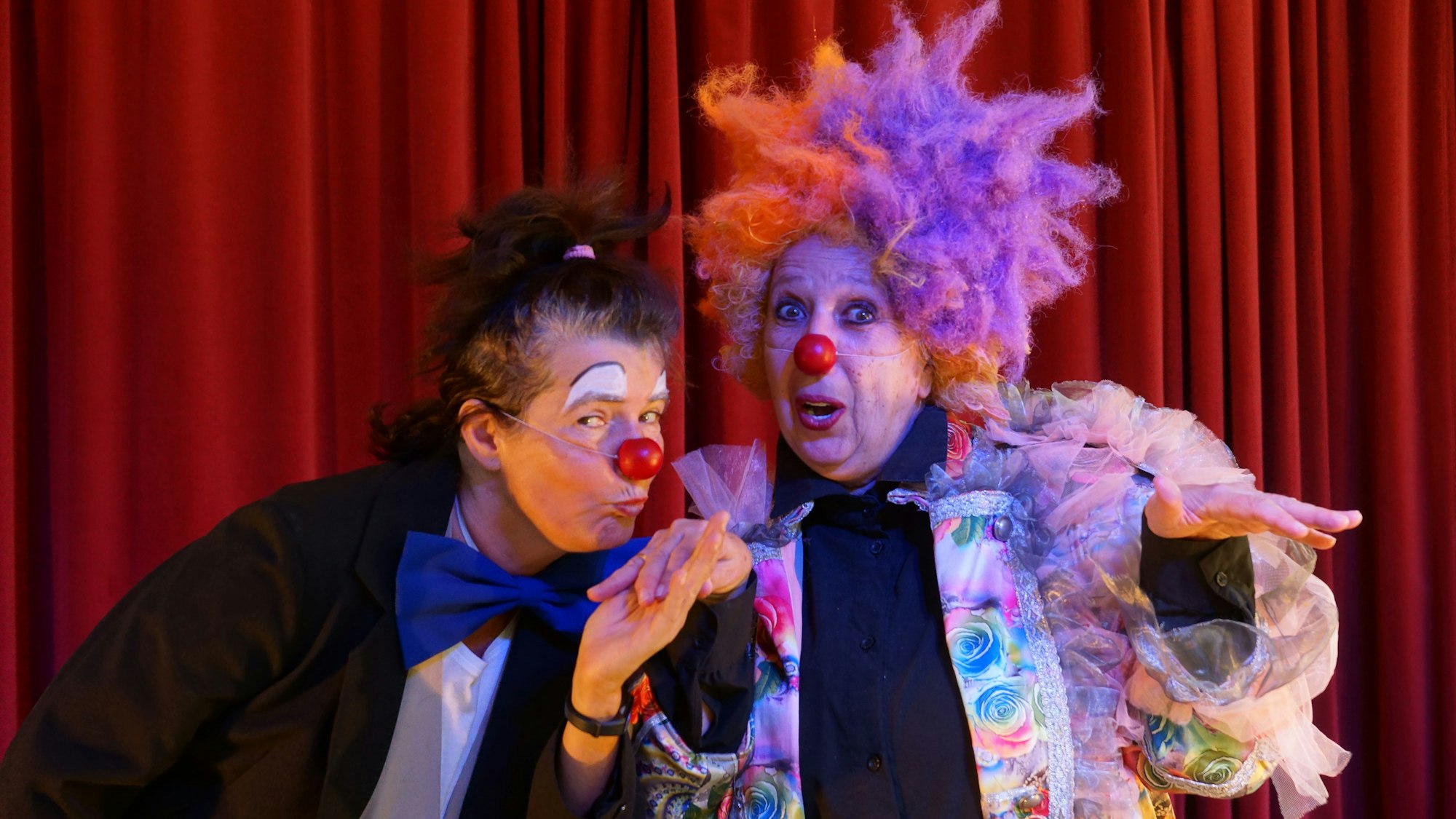 Zwei Clowninnen stehen auf einer Bühne.
