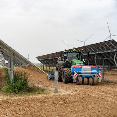 Agri-Solar in Jackerath: Solarpaneele und Trecker sind auf einem Acker zu sehen.