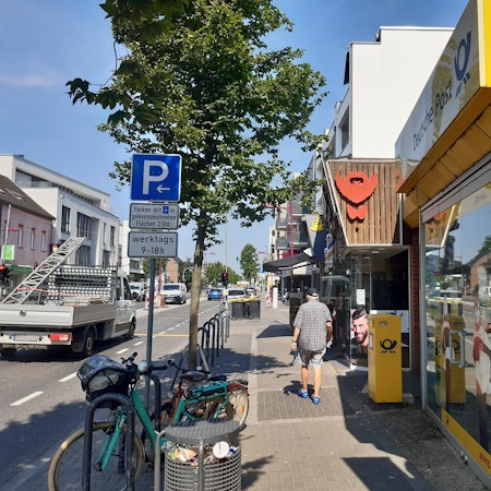 Auf dem Bild ist die Kerpener Straße rund um das Café Dackweiler zu sehen, ein älterer Herr flaniert über den Bürgersteig.