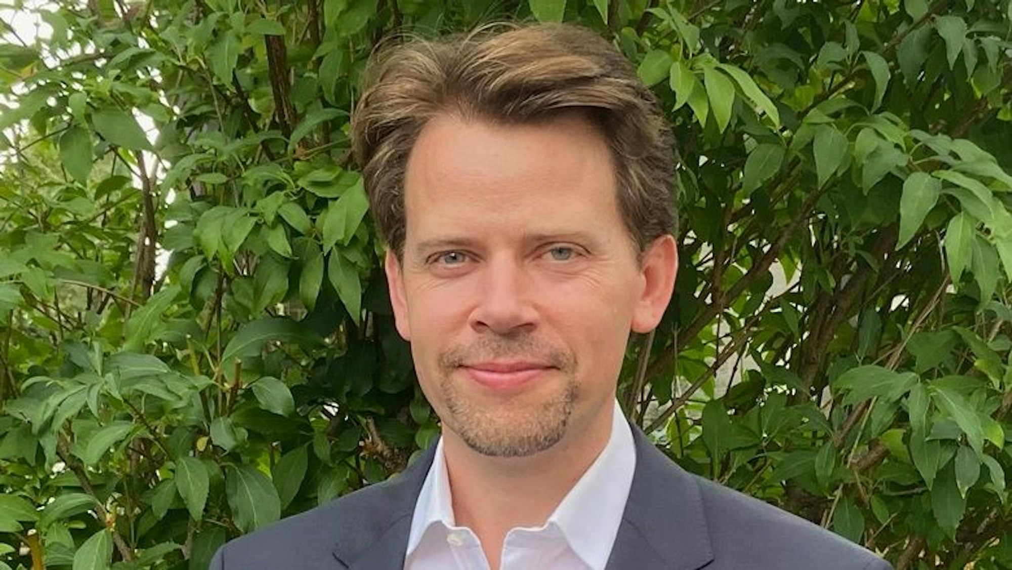 Arne von Boetticher (41) aus Leichlingen steht vor eine grünen Hecke.