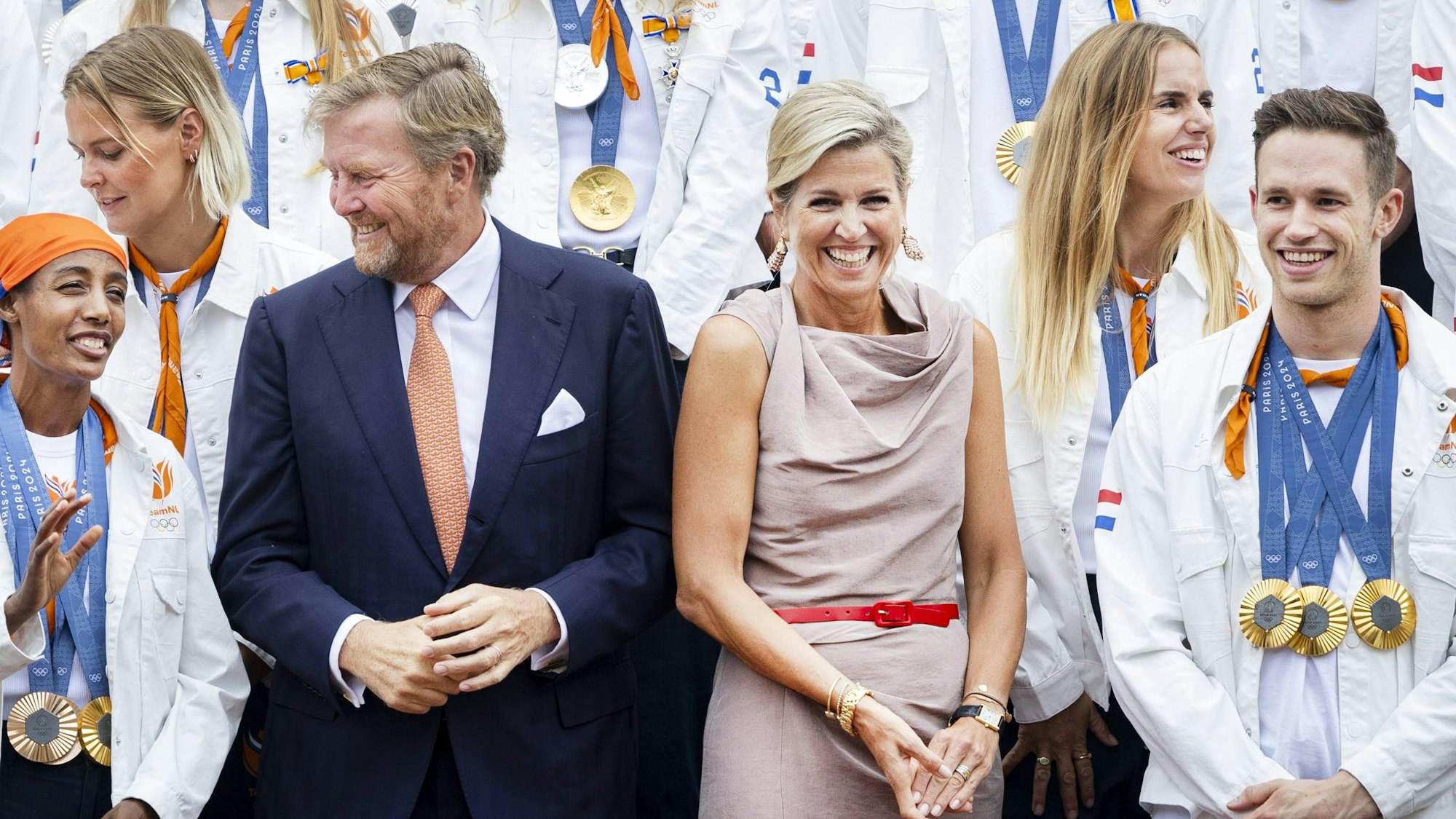 König Willem-Alexander unterhält sich mit der dreifachen Goldmedaillengewinnerin (Tokio und Paris) und Leichtathletin Sifan Hassan, während Königin Máxima neben dem dreifachen Goldmedaillengewinner im Radsport Harrie Lavreysen strahlt.