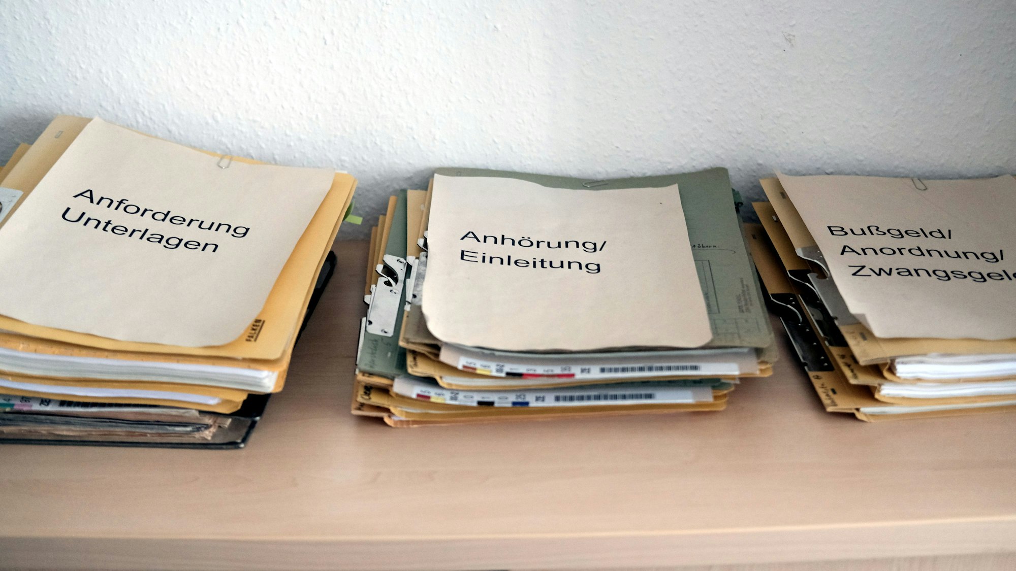 Aktenstapel liegen auf einem Regal.