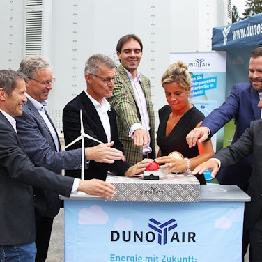 Rechts und links von NRW-Ministerin Mona Neubaur stehen einige Männer. Sie alle drücken auf einen roten Buzzer, um eine Windkraftanlage in Betrieb zu nehmen.