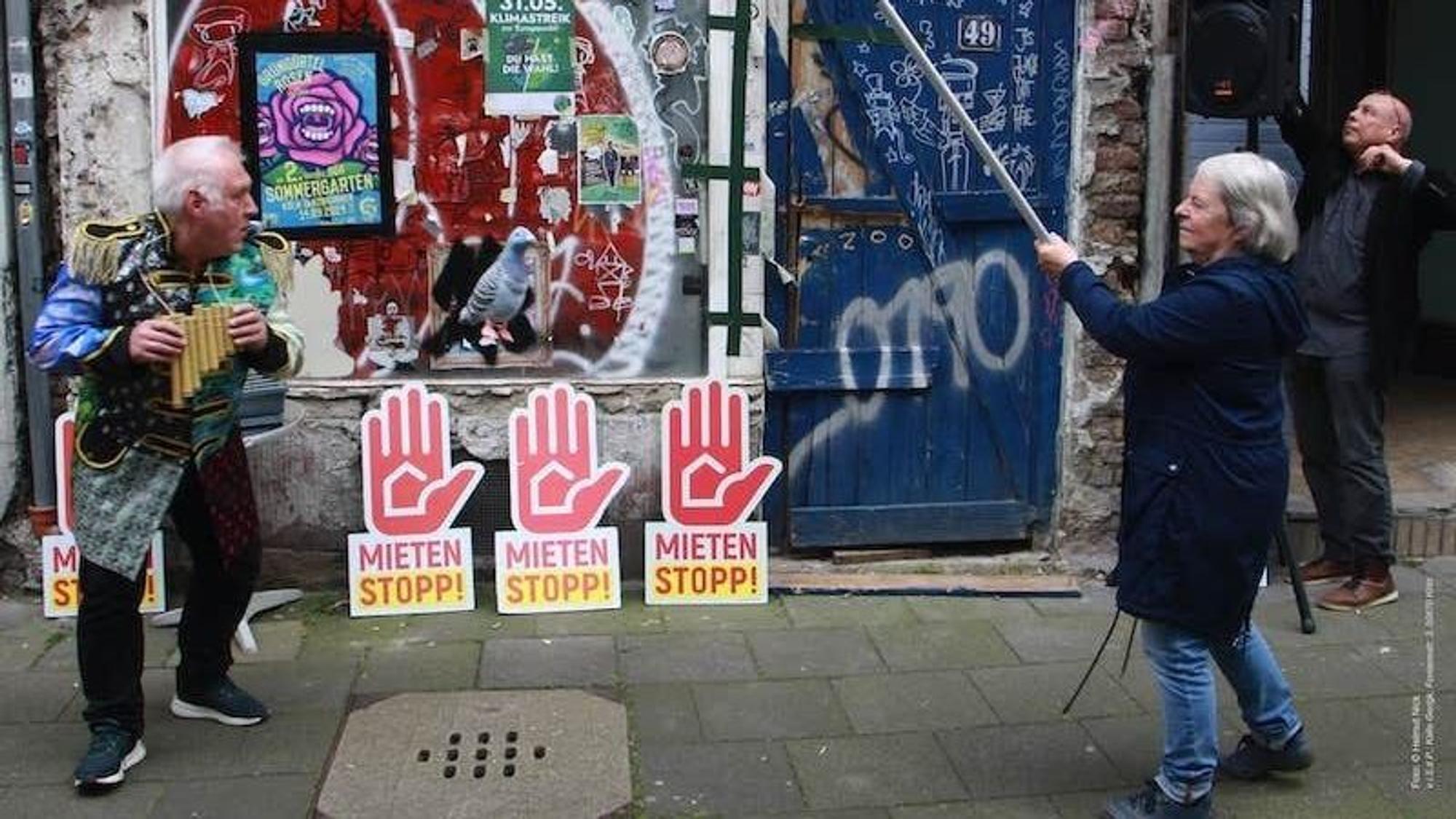 Die Fassade des leerstehenden "Taubenhauses" ist zu sehen. Davor Mahnschilder mit der Aufschrift "Mieten stoppen".