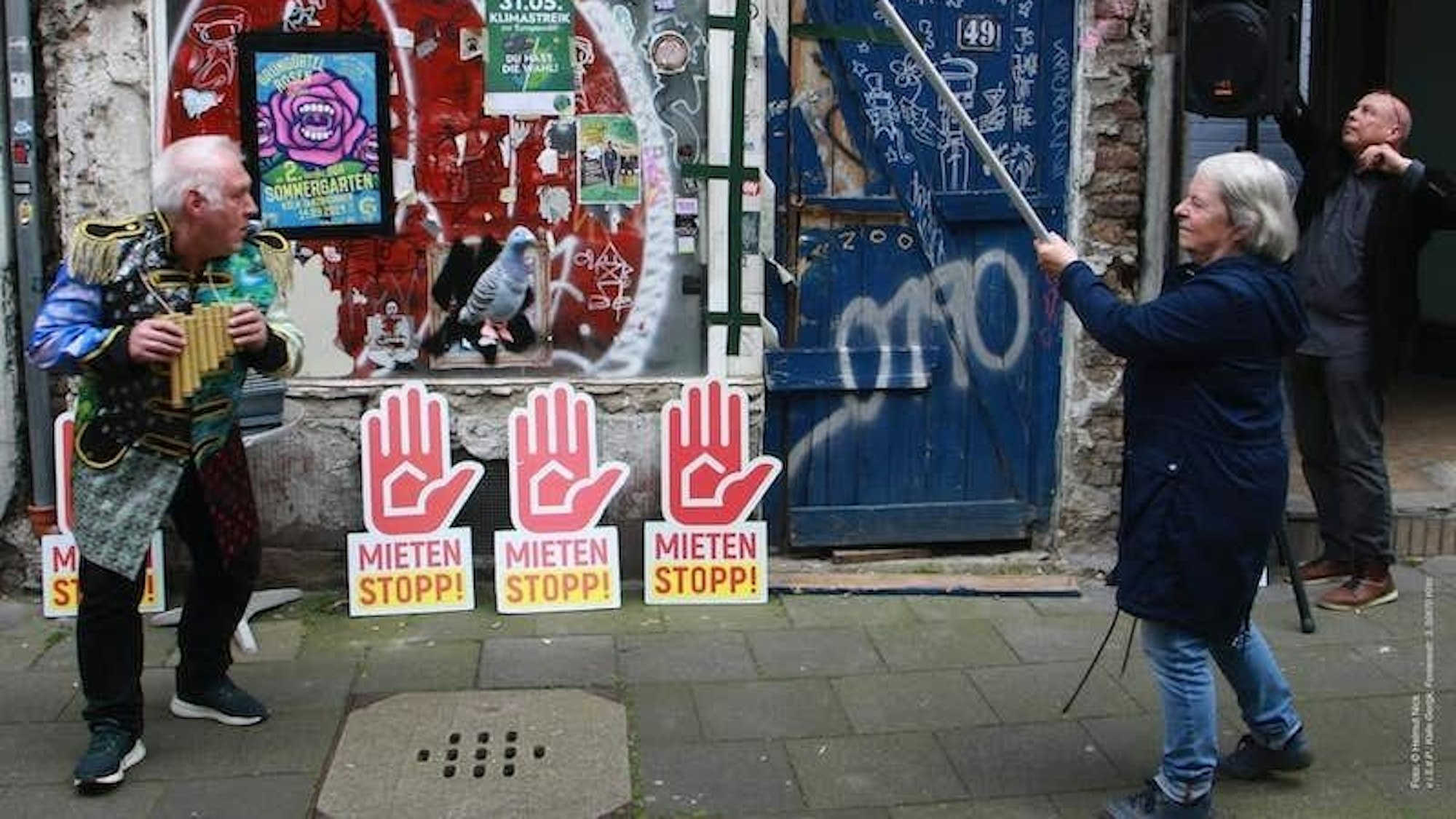 Die Fassade des leerstehenden "Taubenhauses" ist zu sehen. Davor Mahnschilder mit der Aufschrift "Mieten stoppen".