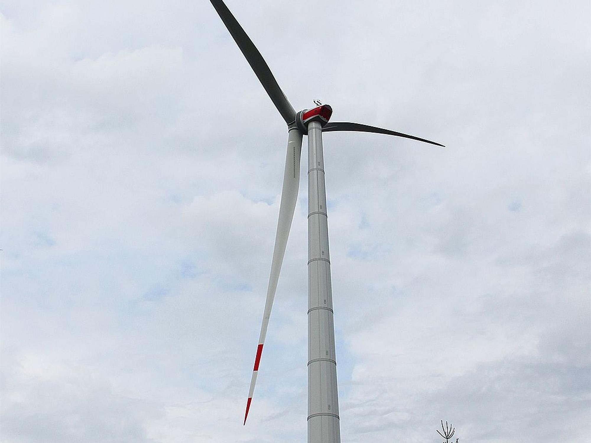 Das Bild eine Windenergieanlage in Dahlem vor dem Hintergrund eines bewölkten Himmels.