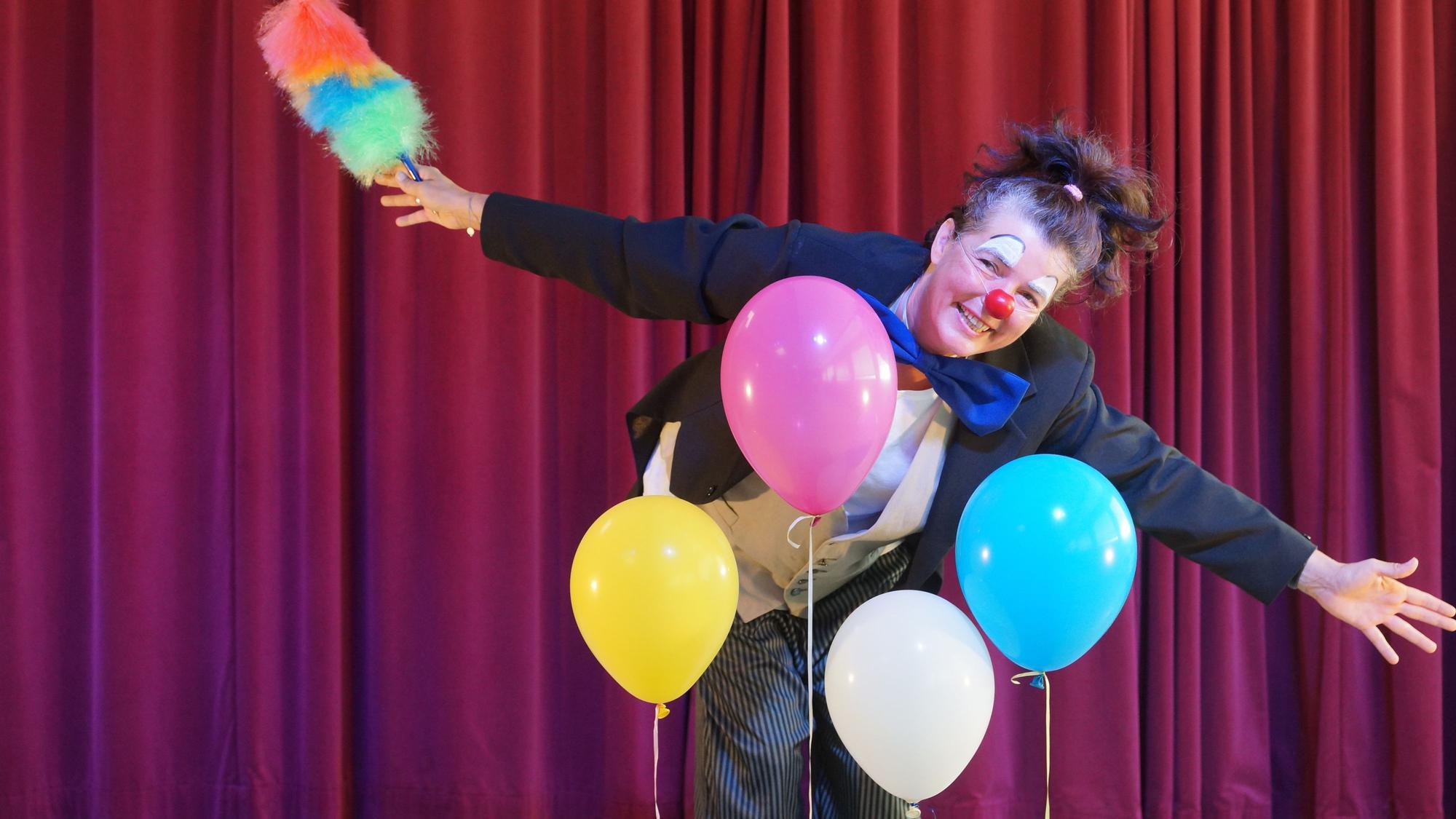 Eine Clownin steht auf einer Bühne.