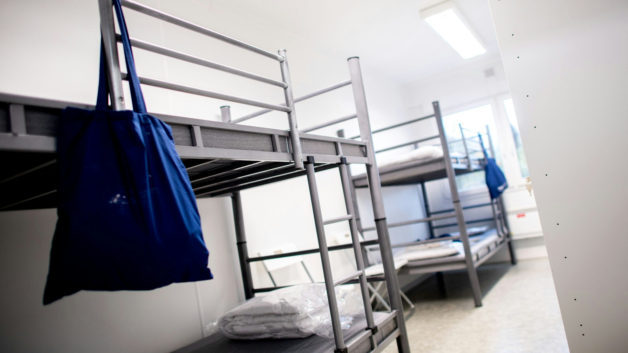 Mehrere Betten stehen in einem Wohncontainer einer Flüchtlingsunterkunft.
