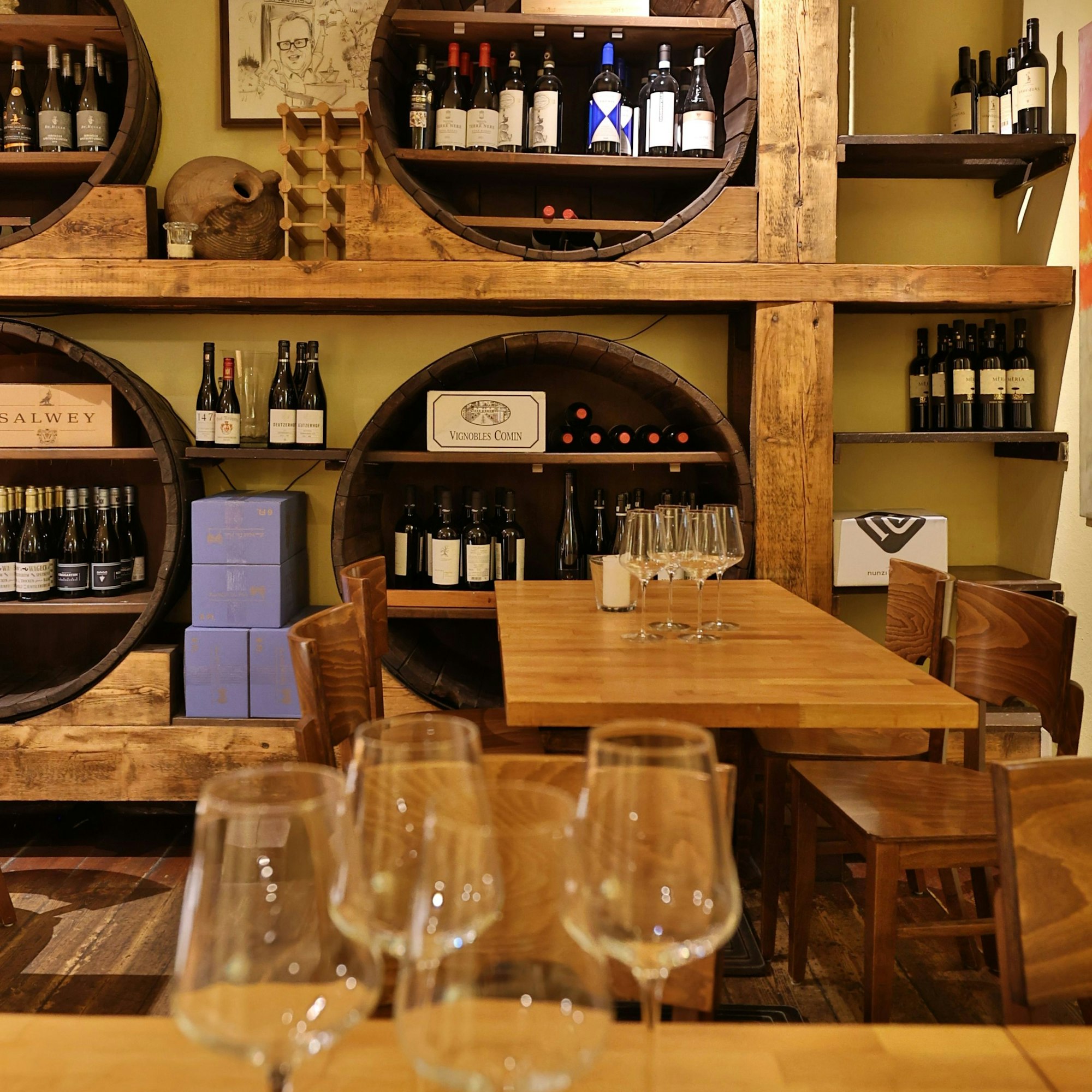 Gastraum mit Weinflaschen, die in Fass ähnlichen Regalen liegen.