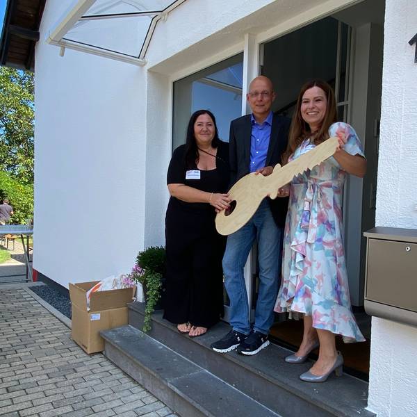 Gruppenleiterin Alexandra Blömeling, Stefan Sudek-Wehr und Sarah Eichhorst (v.l.) bei der symbolischen Schlüsselübergabe mit einem großen Holzschlüssel.