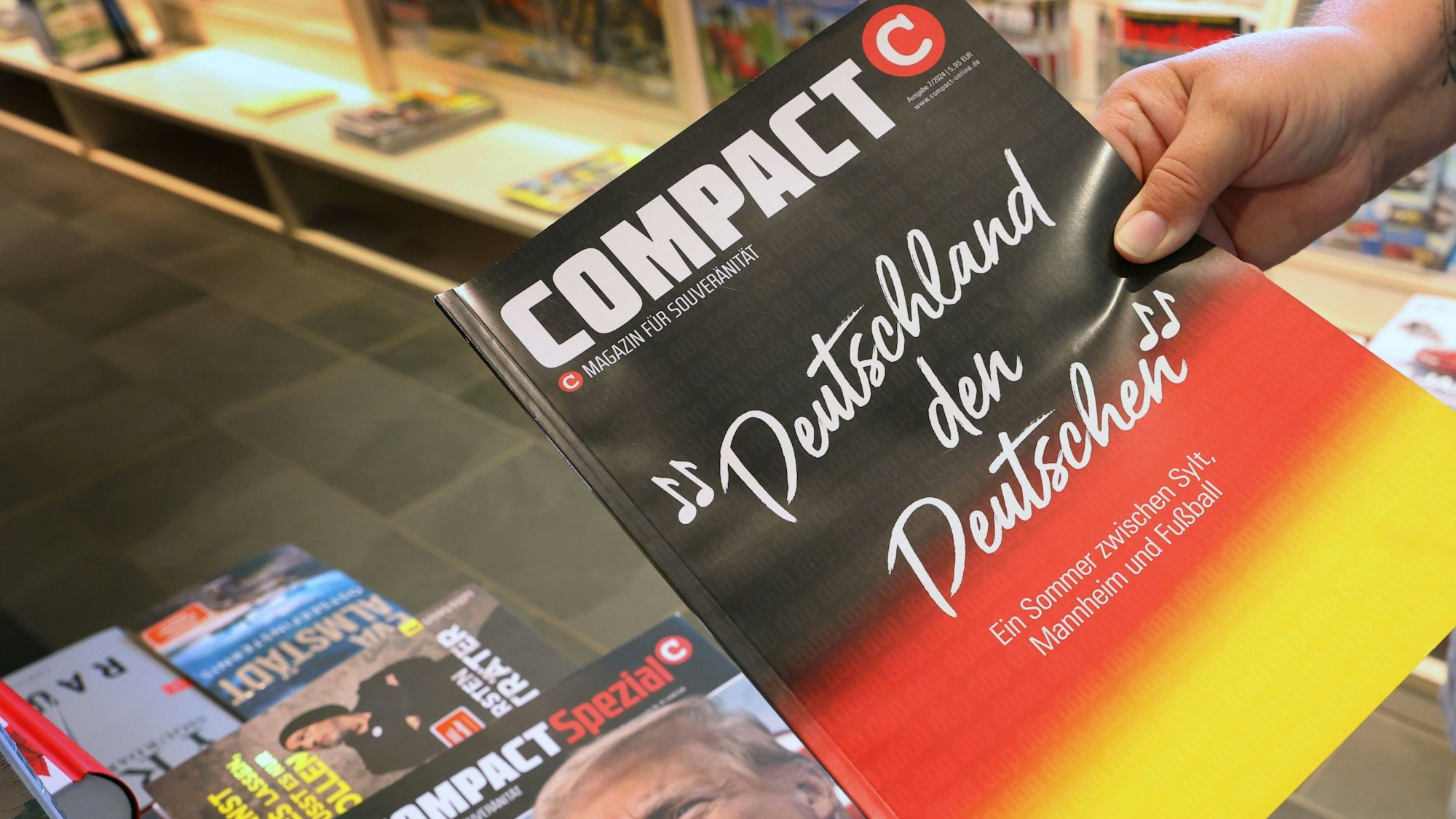 Eine Mitarbeiterin einer Bahnhofsbuchhandlung hält eine Ausgabe des Magazins „Compact“, um es danach aus dem Sortiment zu nehmen. (Archivbild)