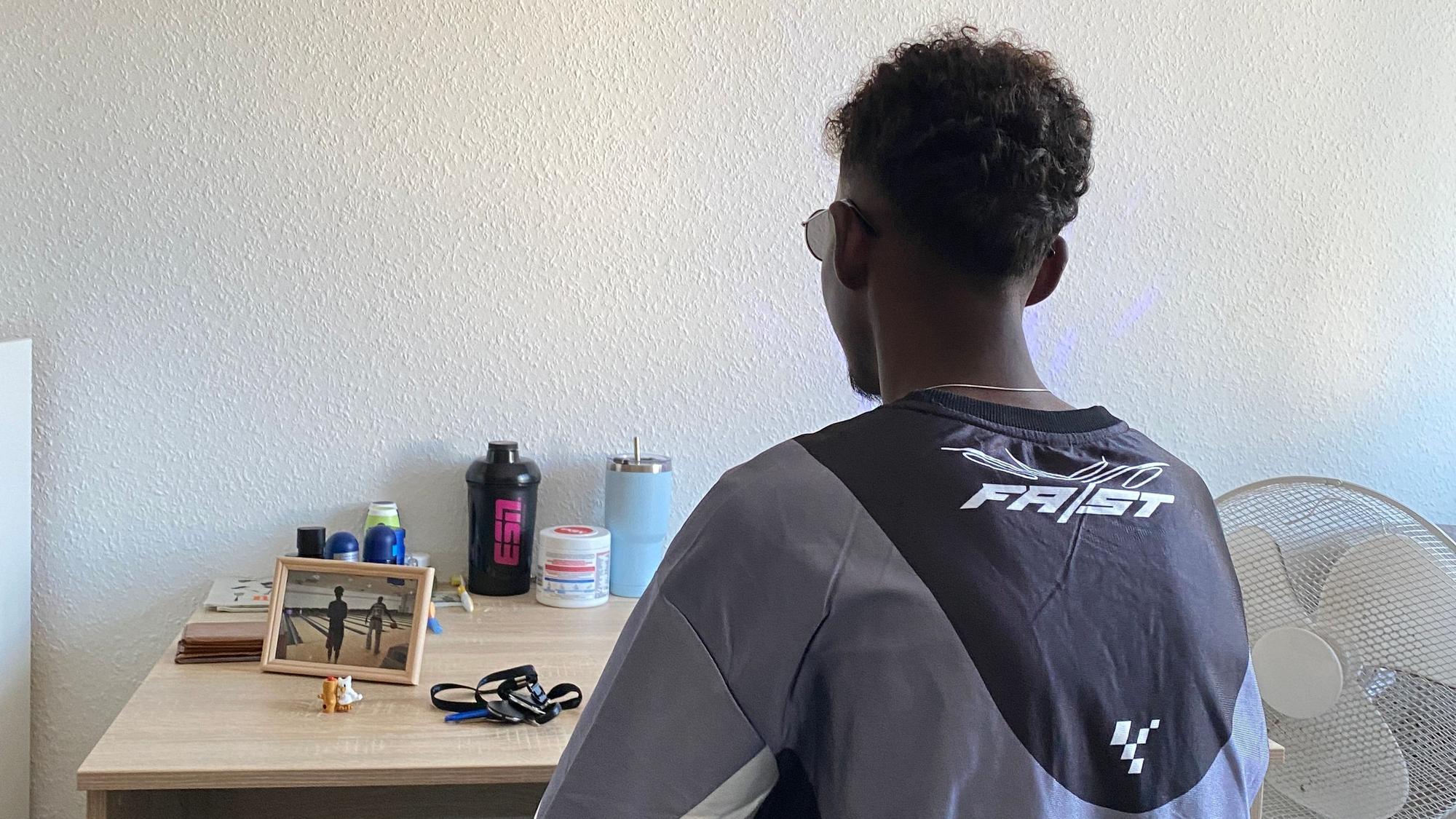 Ein Junge sitzt mit dem Rücken zum Betrachter vor einem Tisch.