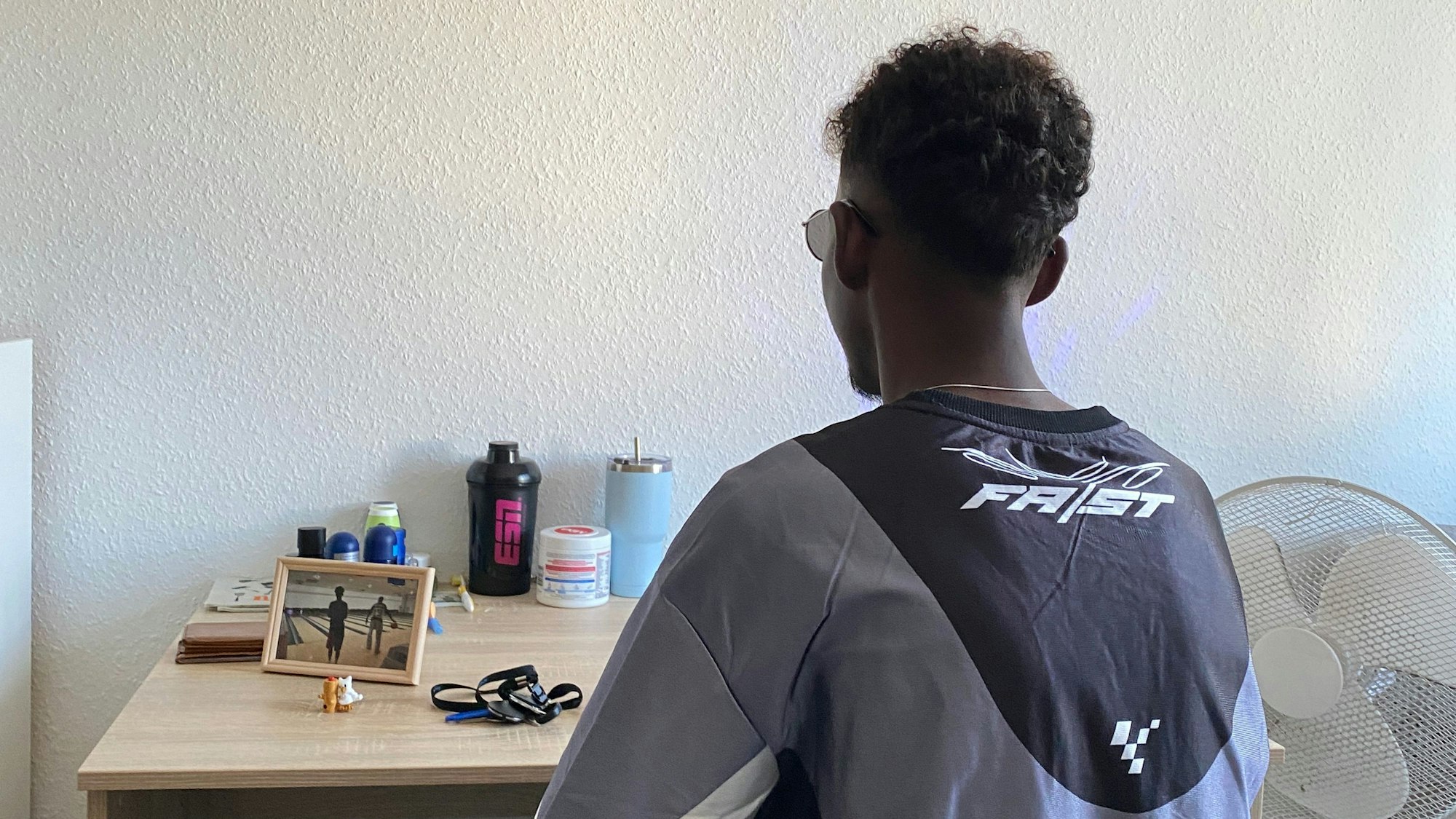 Ein Junge sitzt mit dem Rücken zum Betrachter vor einem Tisch.