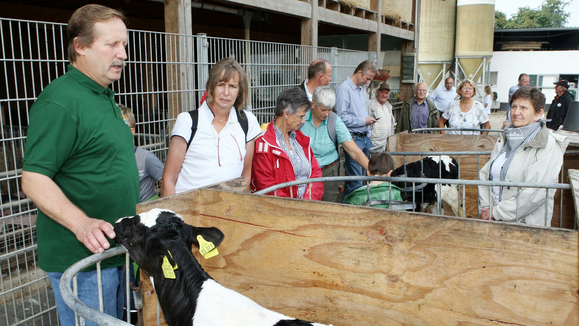 Albert Trimborn steht an einer Kälberbox und erklärt die Landwirtschaft auf dem Gut Schiefelbusch.