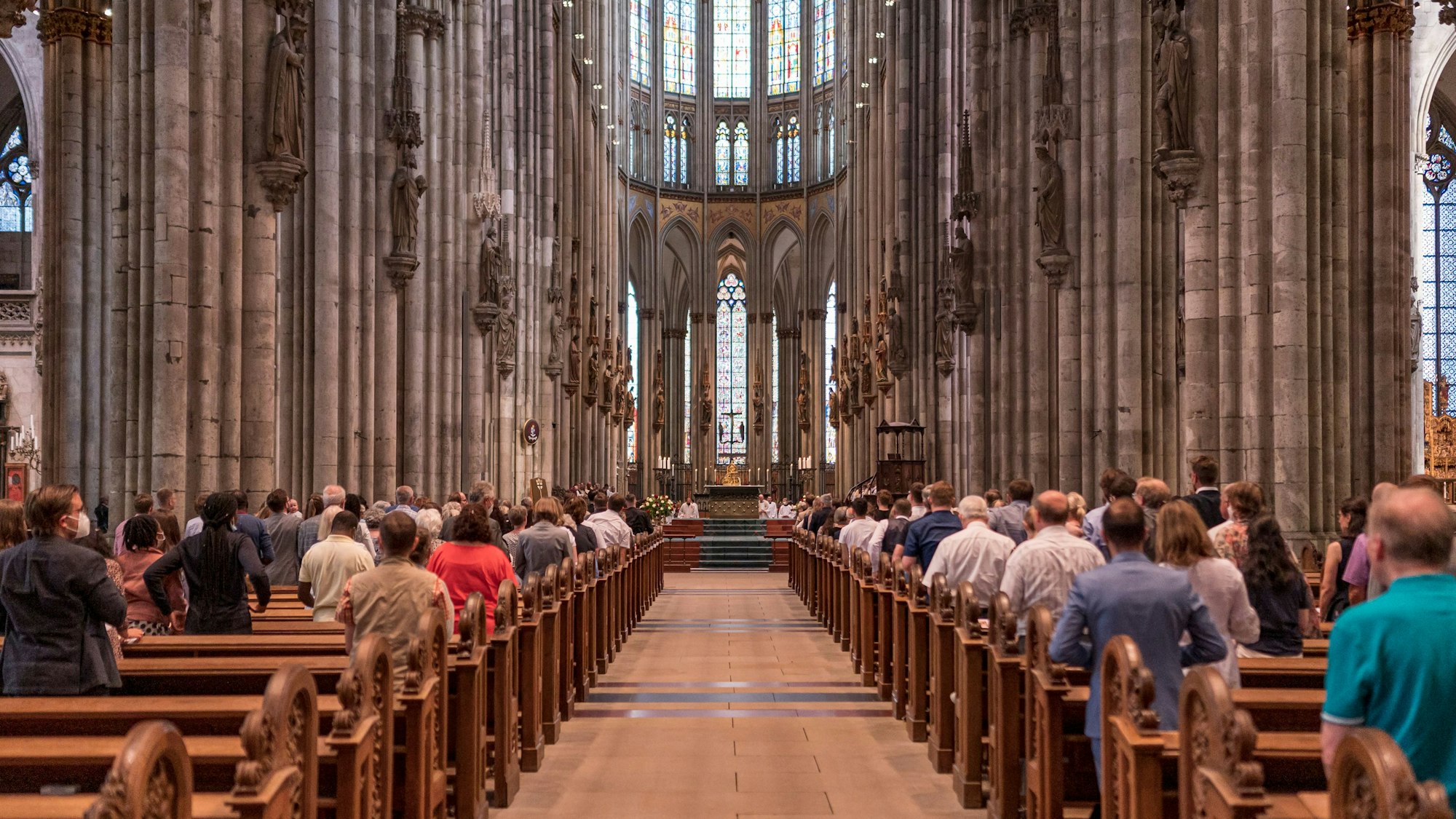 Kölner Dom von Innen, Menschen stehen vor den Bänken