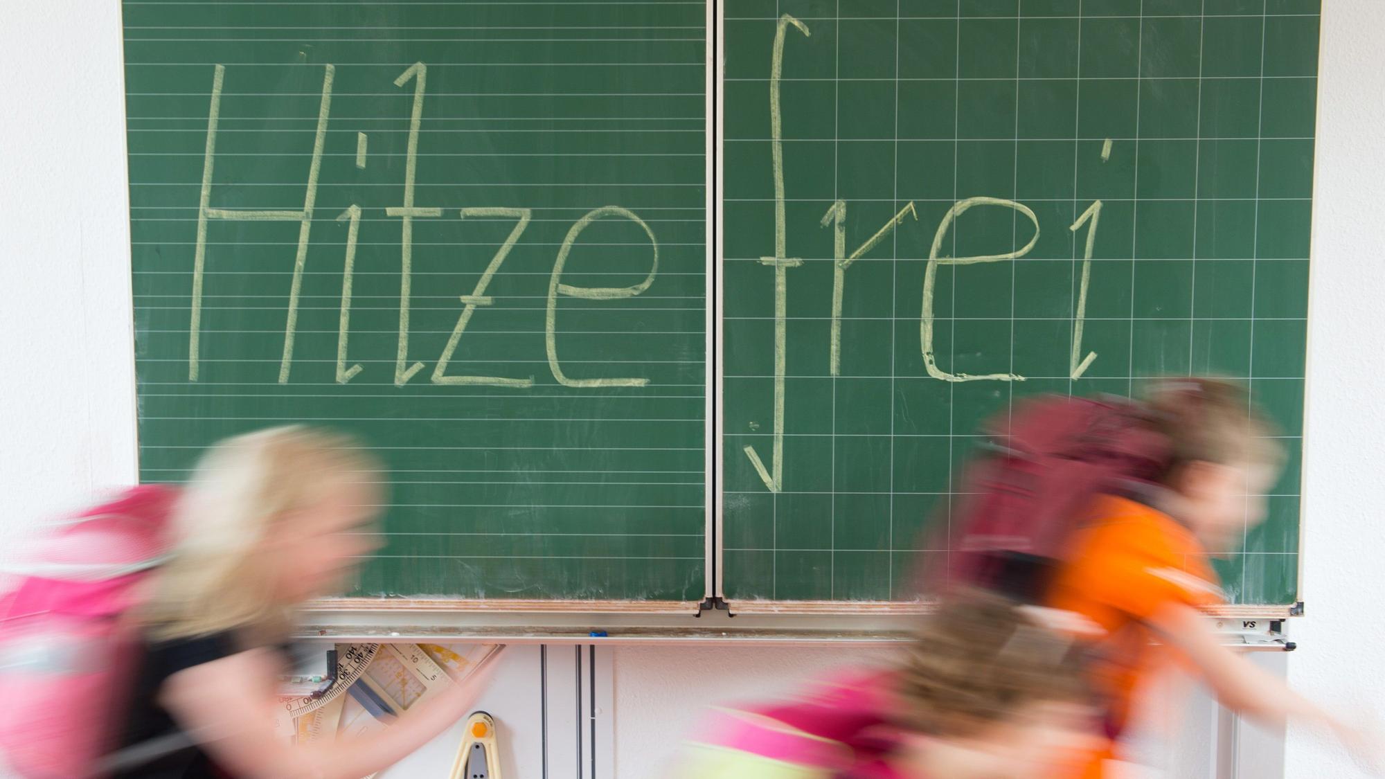Kinder rennen an einer Tafel vorbei mit der Aufschrift "Hitzefrei".